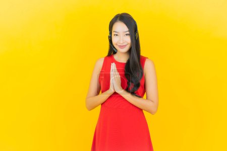 Téléchargez les photos : Portrait belle jeune femme asiatique avec casque pour la communication et le service de centre d'appels de soutien sur fond jaune - en image libre de droit