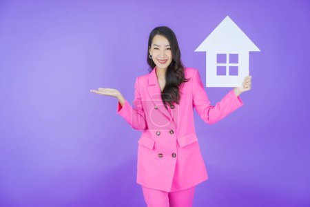 Téléchargez les photos : Portrait belle jeune femme asiatique avec maison ou maison signe de papier sur fond de couleur - en image libre de droit