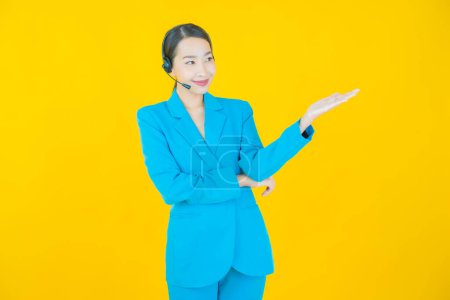 Téléchargez les photos : Portrait belle jeune femme asiatique avec centre d'appels centre de service à la clientèle sur fond de couleur jaune - en image libre de droit