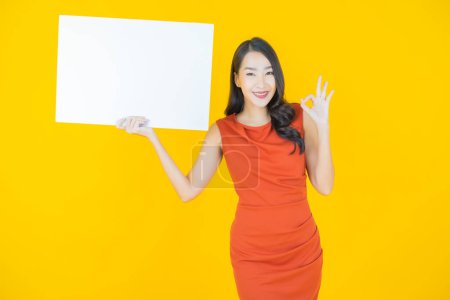 Téléchargez les photos : Portrait belle jeune femme asiatique avec panneau blanc vide sur fond de couleur - en image libre de droit