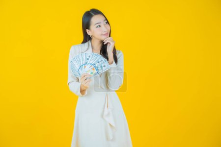 Foto de Retrato hermosa joven asiática mujer sonrisa con un montón de dinero en efectivo y dinero en color de fondo - Imagen libre de derechos