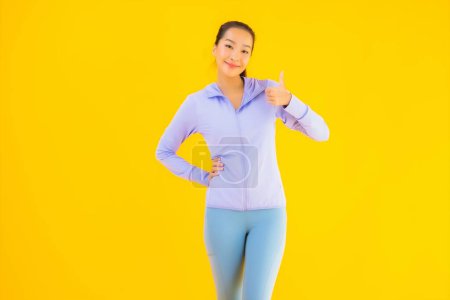 Téléchargez les photos : Portrait belle jeune femme de sport asiatique avec des vêtements de sport prêt pour l'exercice sur fond jaune isolé - en image libre de droit