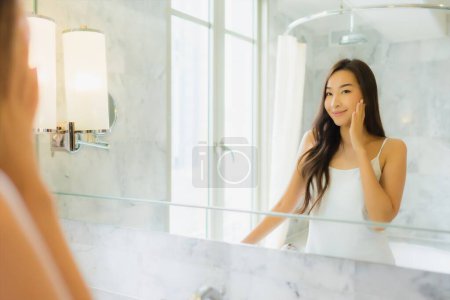Photo for Portrait beautiful young asian woman check up and make up her face on mirror in bathroom interior - Royalty Free Image