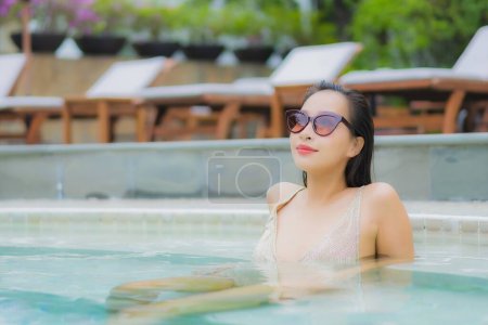 Téléchargez les photos : Portrait belle jeune femme asiatique se détendre sourire autour de la piscine extérieure dans la station hôtelière pour les vacances de loisirs - en image libre de droit