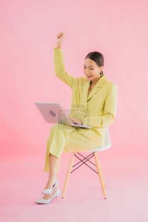 Téléchargez les photos : Portrait belle jeune femme d'affaires asiatique utiliser ordinateur portable sur fond de couleur - en image libre de droit