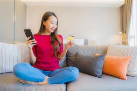 Foto de Retrato hermosa joven asiática mujer uso inteligente teléfono móvil con tarjeta de crédito para compras en línea - Imagen libre de derechos