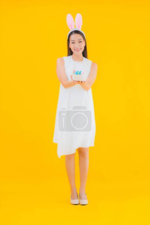 Foto de Retrato hermosa joven asiática mujer con huevo de Pascua en amarillo aislado fondo - Imagen libre de derechos