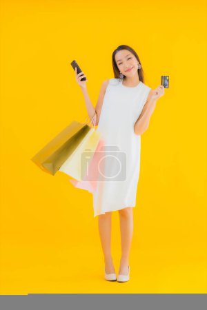 Photo for Portrait beautiful young asian woman with shopping bag from retails department store on yellow isolated background - Royalty Free Image