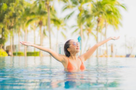 Photo for Portrait beautiful young asian woman relax smile leisure around outdoor swimming pool nearly sea beach ocean at sunset time for vacation - Royalty Free Image