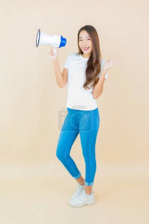 Téléchargez les photos : Portrait belle jeune femme asiatique utiliser mégaphone pour la communication sur fond de couleur crème - en image libre de droit