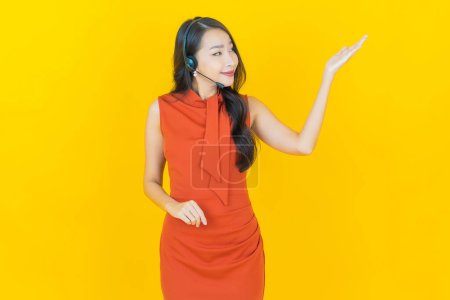 Foto de Retrato hermosa mujer asiática joven con centro de atención al cliente centro de atención al cliente en fondo de color amarillo - Imagen libre de derechos