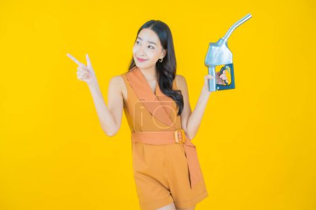 Photo for Portrait beautiful young asian woman feul gas pump on color background - Royalty Free Image