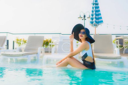 Foto de Retrato hermosa joven mujer asiática feliz sonrisa relajarse alrededor de la piscina al aire libre en el complejo hotelero para vacaciones de viaje - Imagen libre de derechos