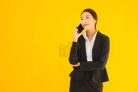 Photo for Portrait beautiful young business asian woman with smart mobile phone and coffee cup on yellow isolated background - Royalty Free Image