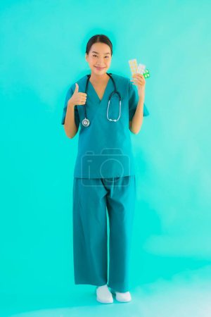 Téléchargez les photos : Portrait belle jeune asiatique médecin femme avec pilule ou médicament et médecine sur fond bleu isolé - en image libre de droit