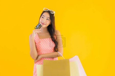 Photo for Portrait beautiful young asian woman with colorful shopping bag with smart mobile phone and credit card on yellow isolated background - Royalty Free Image