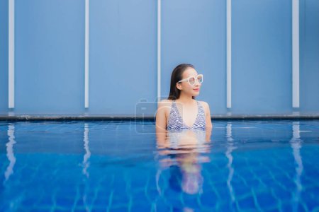 Téléchargez les photos : Portrait belle jeune femme asiatique se détendre sourire autour de la piscine extérieure pour des vacances de loisirs - en image libre de droit