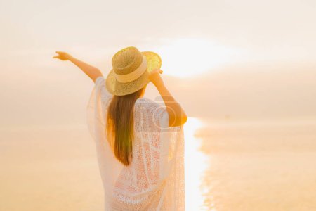 Téléchargez les photos : Portrait belle jeune femme asiatique se détendre sourire loisirs autour de la mer extérieure plage océan au coucher du soleil temps des vacances - en image libre de droit