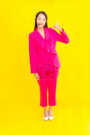 Photo for Portrait beautiful young asian woman with headset and headphone for call center contact on yellow background - Royalty Free Image