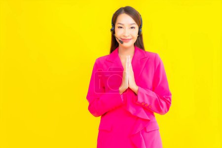 Photo for Portrait beautiful young asian woman with headset and headphone for call center contact on yellow background - Royalty Free Image