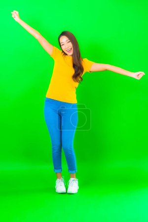 Foto de Retrato hermosa joven asiática mujer sonrisa con acción en verde aislado fondo - Imagen libre de derechos