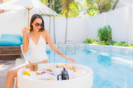 Photo for Portrait beautiful young asian woman happy smile with floating breakfast in tray on swimming pool - Royalty Free Image