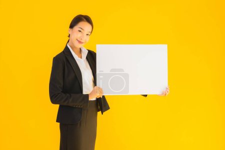 Téléchargez les photos : Beau portrait jeune asiatique femme montrer vide blanc tableau sur jaune isolé fond - en image libre de droit