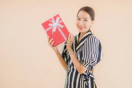 Photo for Portrait beautiful young asian woman with red gift box on brown background - Royalty Free Image