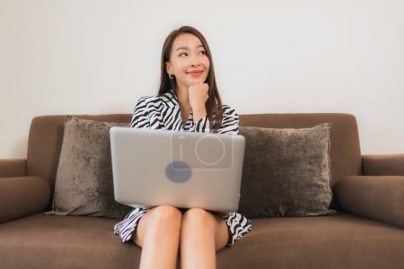 Photo for Portrait beautiful young asian woman use computer laptop on sofa in living room interior area - Royalty Free Image