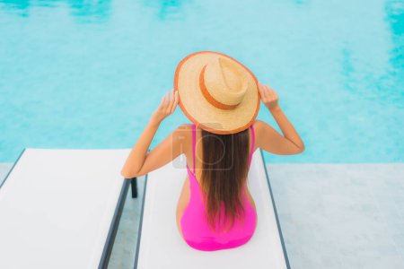 Téléchargez les photos : Portrait belle jeune femme asiatique relax sourire autour de la piscine extérieure dans la station hôtelière pour des vacances de voyage - en image libre de droit