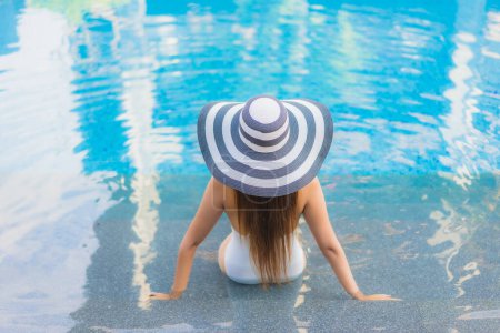 Téléchargez les photos : Portrait belle jeune femme asiatique se détendre sourire autour de la piscine extérieure dans hôtel station balnéaire presque mer plage océan - en image libre de droit