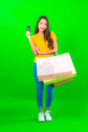 Foto de Retrato hermosa joven mujer asiática con colorido bolso de compras sobre fondo verde - Imagen libre de derechos