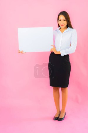 Téléchargez les photos : Portrait belle jeune femme asiatique montrer vide panneau d'affichage blanc sur fond de couleur rose - en image libre de droit