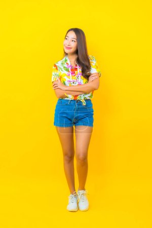 Foto de Retrato hermosa joven asiática mujer usar colorido camisa en amarillo fondo para sonkran festival en Tailandia - Imagen libre de derechos