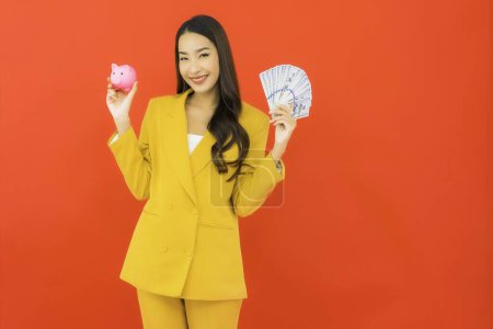Téléchargez les photos : Portrait belle jeune femme asiatique avec beaucoup d'argent et d'argent sur fond rouge - en image libre de droit