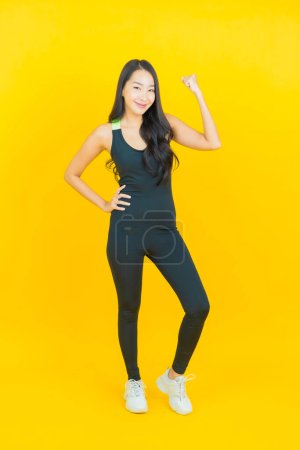 Téléchargez les photos : Portrait belle jeune femme asiatique porter tenue de gym prêt pour l'exercice sur fond de couleur jaune - en image libre de droit