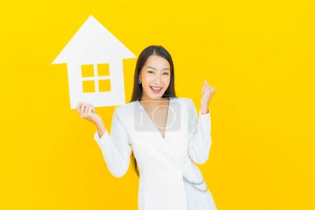 Foto de Retrato hermosa joven mujer asiática con casa o casa cartel de papel sobre fondo de color - Imagen libre de derechos