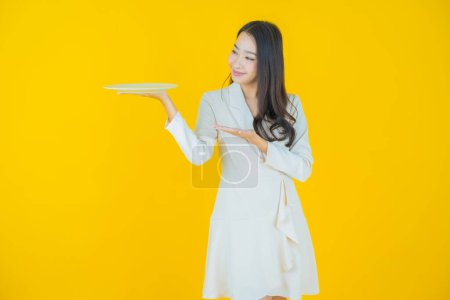 Photo for Portrait beautiful young asian woman smile with empty plate dish on color background - Royalty Free Image