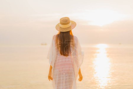 Téléchargez les photos : Portrait belle jeune femme asiatique se détendre sourire loisirs autour de la mer extérieure plage océan au coucher du soleil temps des vacances - en image libre de droit
