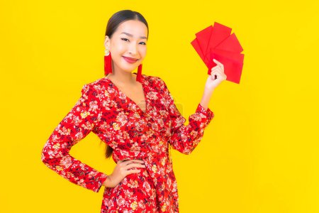 Foto de Retrato hermosa joven asiática mujer con sobres rojos sobre fondo amarillo - Imagen libre de derechos