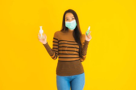 Photo for Portrait beautiful young asian woman with mask alcohol spray and gel bottle in her hand for protect from coronavirus or covid19 on yellow isolated background - Royalty Free Image