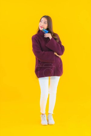 Foto de Retrato hermosa joven asiática mujer con tarjeta de crédito para compras en línea en amarillo aislado fondo - Imagen libre de derechos