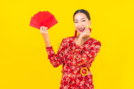 Foto de Retrato hermosa joven asiática mujer con sobres rojos sobre fondo amarillo - Imagen libre de derechos