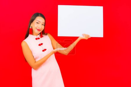 Foto de Retrato hermosa joven asiática mujer show blanco vacío valla publicitaria en rojo fondo - Imagen libre de derechos