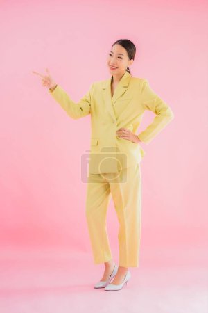 Téléchargez les photos : Portrait belle jeune femme d'affaires asiatique sourire en action sur fond de couleur rose - en image libre de droit