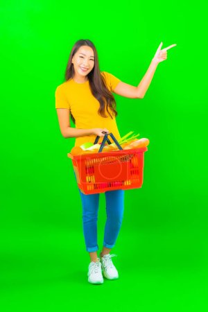 Photo for Portrait beautiful young asian woman with grocery basket and cart from supermarket on green background - Royalty Free Image
