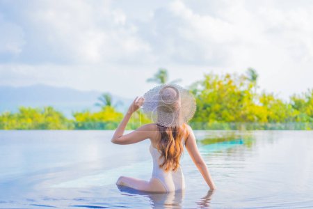 Téléchargez les photos : Portrait belle jeune femme asiatique profiter autour de la piscine extérieure avec vue sur l'océan de mer en voyage vacances - en image libre de droit