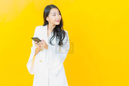 Foto de Retrato hermosa joven mujer asiática sonrisa con teléfono móvil inteligente en el fondo de color - Imagen libre de derechos