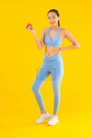 Téléchargez les photos : Portrait belle jeune femme asiatique porter des vêtements de sport prêt à l'exercice avec des fruits de pomme fond isolé - en image libre de droit