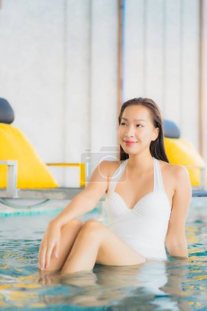 Téléchargez les photos : Portrait belle jeune femme asiatique se détendre sourire autour de la piscine dans la station hôtelière en vacances de voyage - en image libre de droit